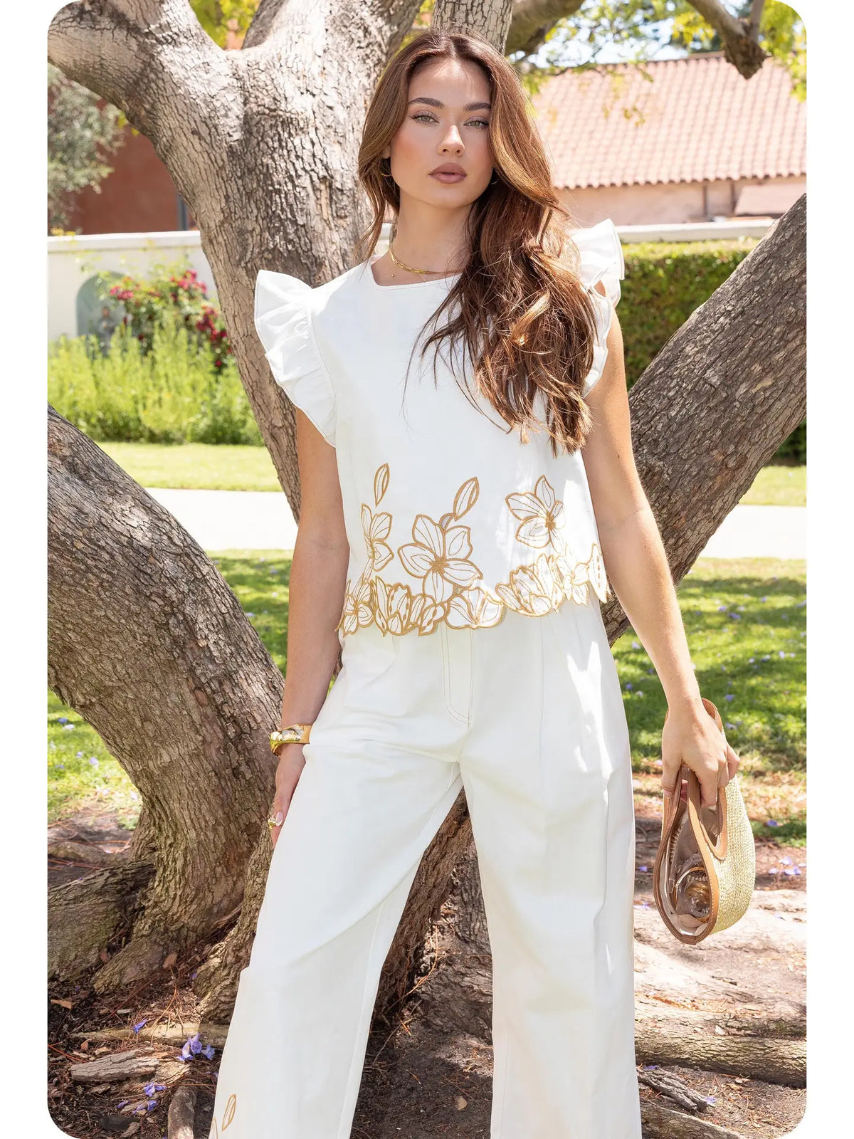 Strut & Bolt off-white twill top with ruffled shoulders, round neckline, and sand floral cut-out embroidery along the hem.